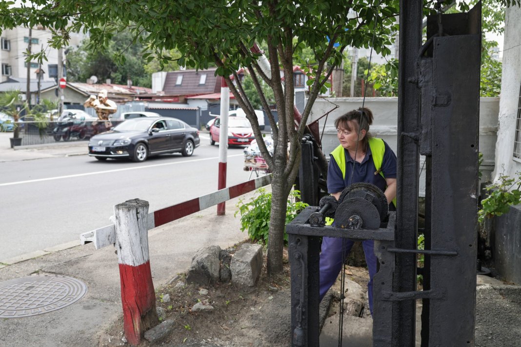 Femeia de 36 de ani care ridică manual o barieră de tren. O fotografie care evidențiază condiția infrastructurii din România.
